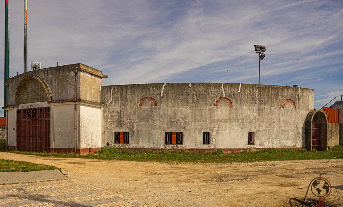 Außenansicht der Stierkampfarena mit geschwungenem Betonbau und rotem Torbogen