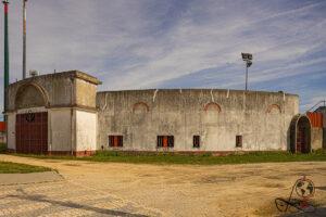 Außenansicht der Stierkampfarena mit geschwungenem Betonbau und rotem Torbogen