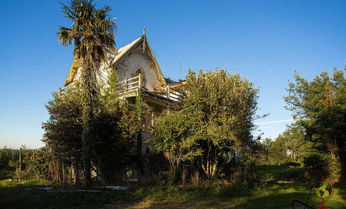 Außenansicht der verlassenen Villa Casa Azul do Conde mit Palmen und verwildertem Garten
