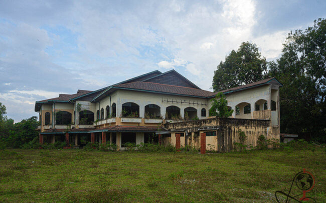 Außenansicht des verlassenen Clubhauses im Golfresort mit verwilderter Wiese