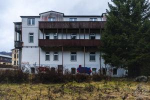 Außenansicht des ehemaligen FDGB-Erholungsheims W. mit weißer Fassade, langen Holzbalkonen und verwildertem Gelände