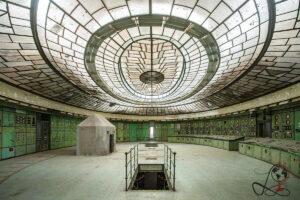 Weitwinkelansicht der historischen Schaltwarte im Kraftwerk Kelenföld mit ovalem Glasdach, grünen Schaltfeldern und einer Bodenöffnung.