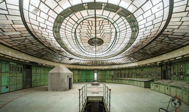 Weitwinkelansicht der historischen Schaltwarte im Kraftwerk Kelenföld mit ovalem Glasdach, grünen Schaltfeldern und einer Bodenöffnung.