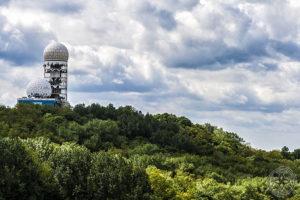 Blick über den bewaldeten Teufelsberg auf die Radarkuppeln der ehemaligen NSA Abhörstation unter wolkigem Himmel
