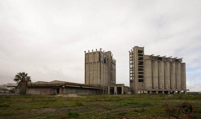 Verlassene Nutasa-Futtersilos in Barreiro mit hohen Betontürmen hinter verwildertem Gelände