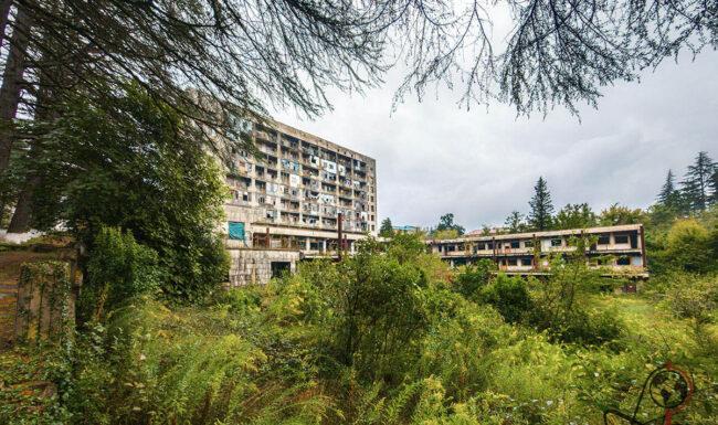 Panoramablick auf den begrünten Innenhof des Sanatoriums Samkurnalo mit überdachtem Durchgang und mehreren Gebäudeteilen