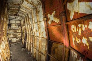 Innenansicht des Bunkers mit rostiger Tür und abgeblätterter roter Wandfarbe