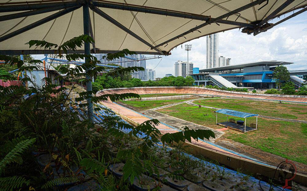 Blick über die überwucherten Tribünen auf die Bahn im Velodrom Pang