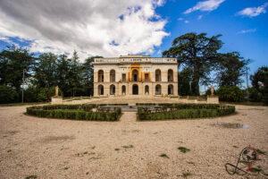 Neoklassizistische Fassade der Villa La Quiete in Treia mit symmetrischem Gartenparterre und hohen Bäumen.