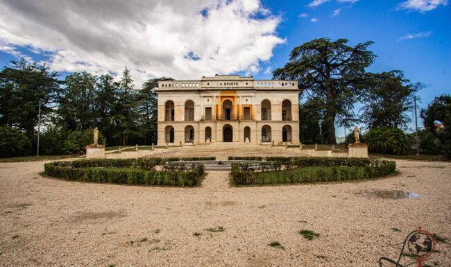 Neoklassizistische Fassade der Villa La Quiete in Treia mit symmetrischem Gartenparterre und hohen Bäumen.